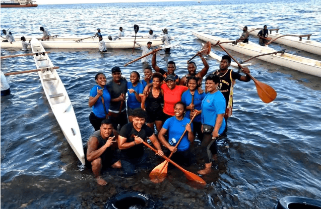 OOCSA paddlers gathered in the water beside outrigger canoes