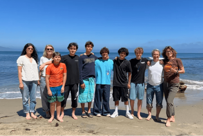 Young volunteers and mentors standing together on a beach